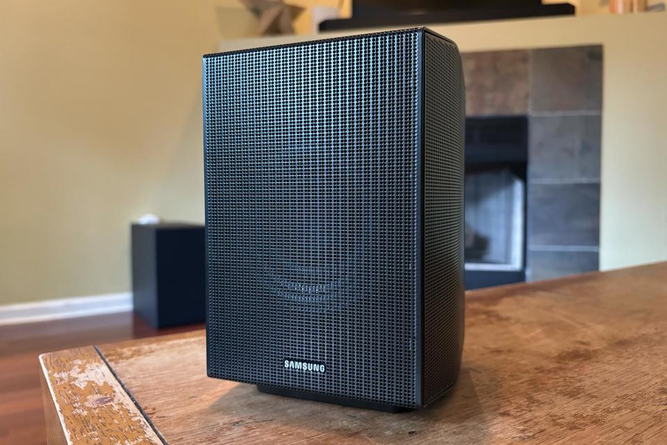 One of the rear speakers for the Q990D sits on a wooden table. 