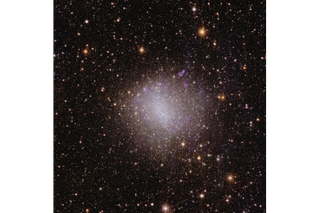 A brilliant pink and white spot of light in the center of the image, surrounded by millions of spots of light representing distant space objects.