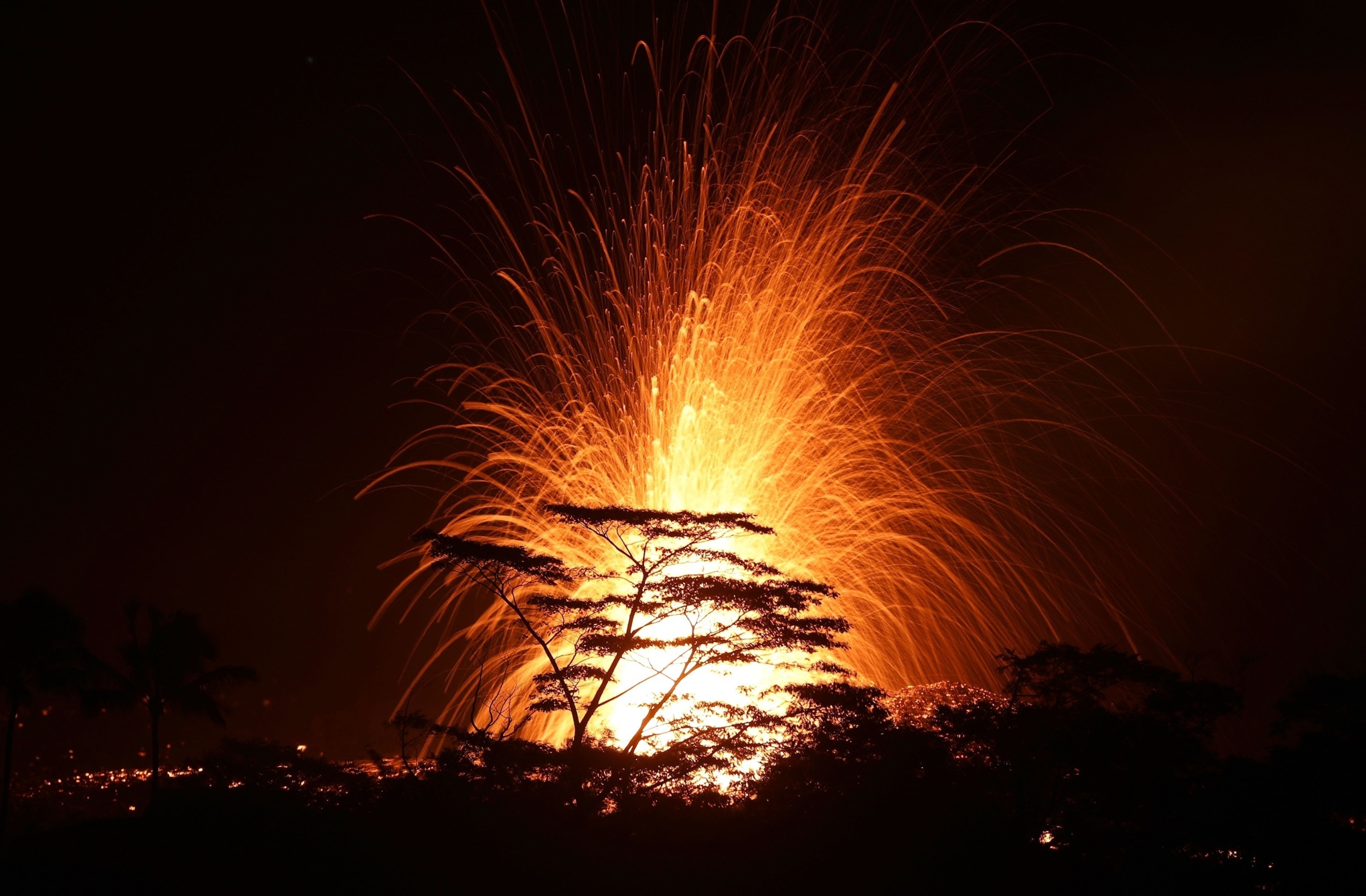 PHOTO: Lava is blurred as it erupts from a fissure on Kilauea volcano, above the treetops, on the Big Island of Hawaii on May 17, 2018 in Kapoho, Hawaii.