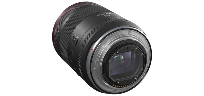 A close-up view of a Canon camera lens.  The lens features a variety of switches and markings and is mostly black with a red accent ring on the end.  You can see the internal glass elements and the electronic contacts on the mounting side.