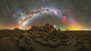 A Milky Way rainbow photographed over a mound of rocks in the Atacama Desert, Chile