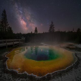 The Milky Way photographed above Morning Glory Hot Spring in Yellowstone National Park, USA