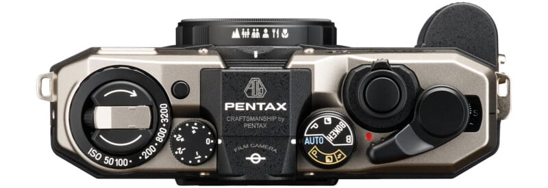 Top down view of a Pentax film camera with various dials, shutter button and ISO setting range from 50 to 3200. The camera body is silver with black accents and the brand "Pentax" displayed prominently in the center.