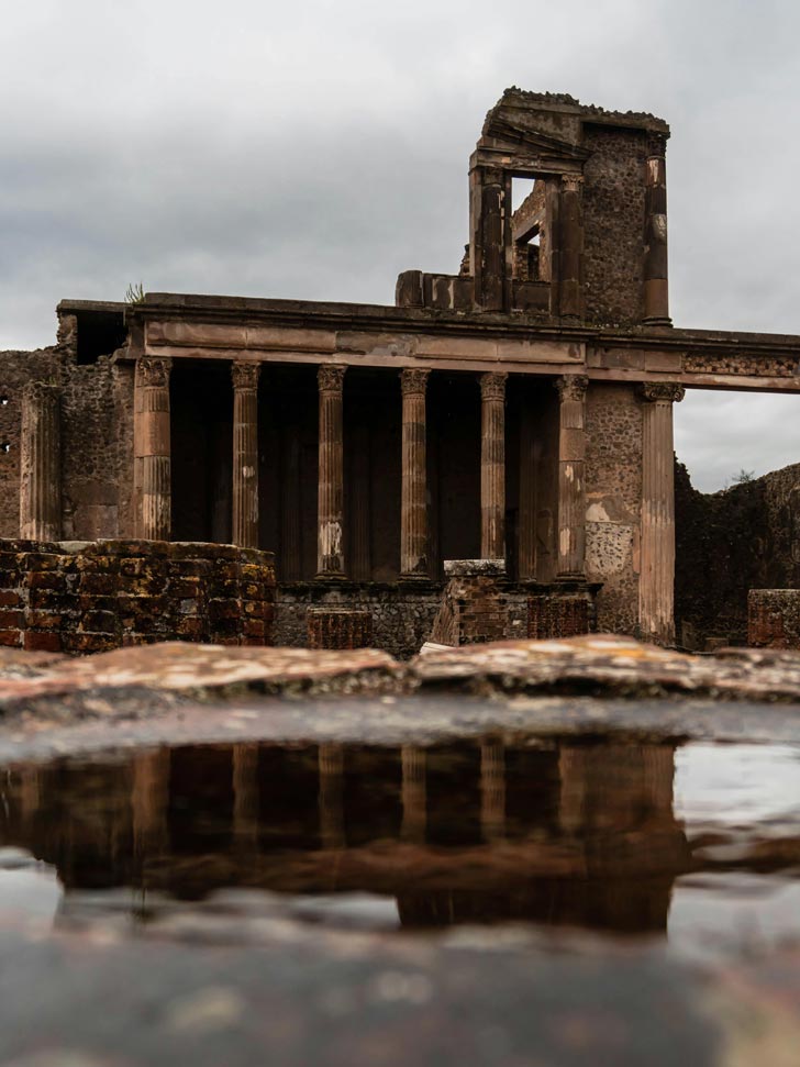 A large puddle sits next to Roman ruins