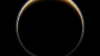 A dark sphere bounded by a brown-yellow ring that is thicker at the north pole of the sphere